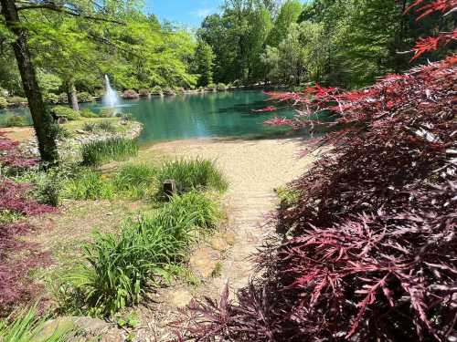 A serene pond surrounded by lush greenery and vibrant red foliage under a clear blue sky.