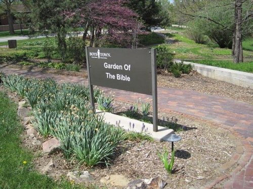 Sign for "Garden of the Bible" at Boys Town, surrounded by greenery and a brick pathway.