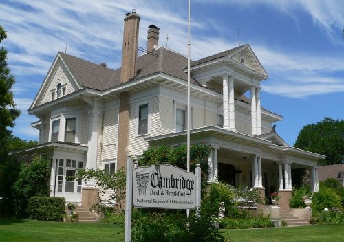 A large, historic Victorian-style house with a sign for "Cambridge Bed & Breakfast" in front, surrounded by greenery.