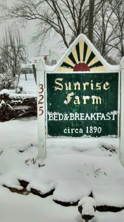Sign for Sunrise Farm Bed & Breakfast, established 1890, surrounded by snow in a winter landscape.