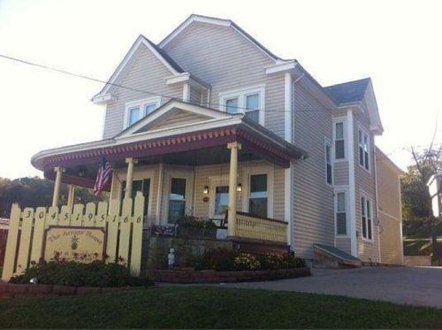 A large, two-story house with a porch, American flag, and a sign reading "The Amber House" in a residential area.
