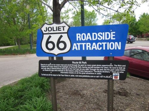 Sign for Route 66 Park in Joliet, featuring "Roadside Attraction" and information about local attractions and events.