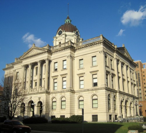 Historic building with a dome, ornate architecture, and columns, set against a blue sky with scattered clouds.