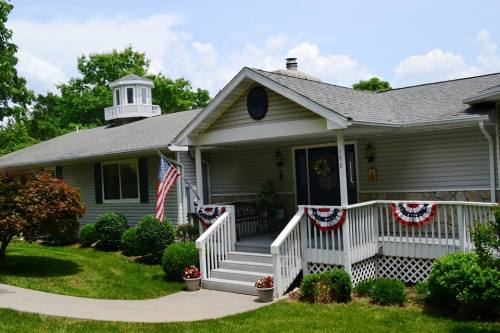 A charming house with a front porch, decorated with red, white, and blue bunting, surrounded by green grass and trees.
