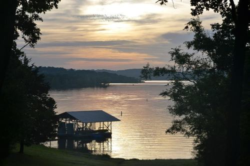 A serene lake at sunset, with a dock silhouetted against the colorful sky and calm water.