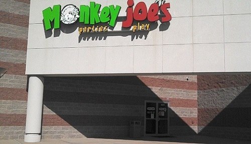 Colorful sign for "Monkey Joe's" featuring the words "Parties" and "Play" on a building exterior.