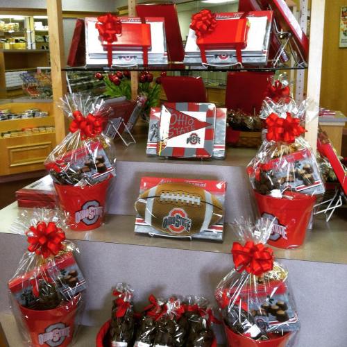 Display of Ohio State-themed gift baskets and treats, decorated with red bows, in a store setting.