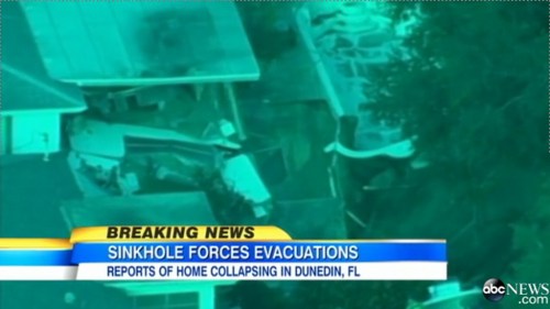 Aerial view of a collapsed home in Dunedin, FL, with a news banner about sinkhole evacuations.