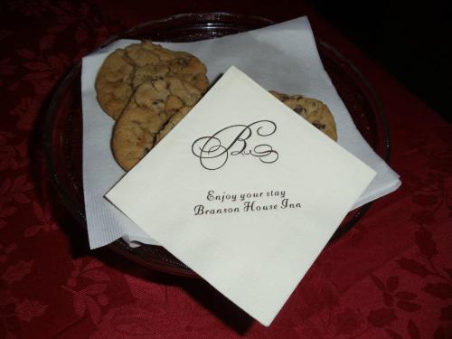A plate of cookies next to a napkin with "Enjoy your stay, Branson House Inn" printed on it, set on a red tablecloth.