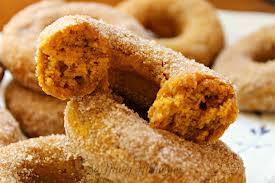 A close-up of cinnamon sugar-coated donuts, with one donut partially bitten, revealing a soft, fluffy interior.