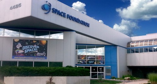 Exterior of the Space Foundation building with a "Discover Space!" banner and a blue sky in the background.