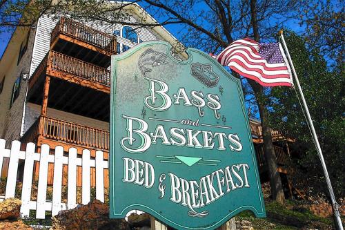 Sign for "Bass and Baskets Bed & Breakfast" with an American flag and a white picket fence in the background.