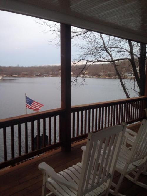 View from a porch with rocking chairs overlooking a lake and an American flag waving in the breeze.