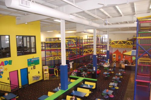 Bright indoor play area with colorful climbing structures, seating, and arcade games. Family-friendly atmosphere.