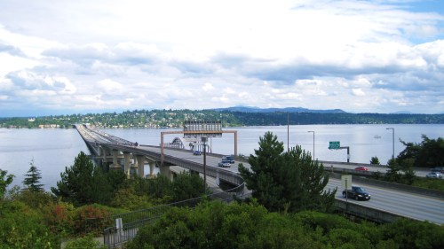 Lacey V. Murrow Memorial Floating Bridge carrying traffic across Lake Washington in Seattle with shoreline houses and mountains in the background