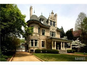 A large, ornate Victorian-style house with a turret, surrounded by greenery and a well-maintained lawn.