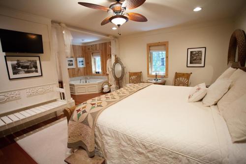 Cozy bedroom with a large bed, decorative quilt, and a bathroom area featuring a tub and wooden accents.