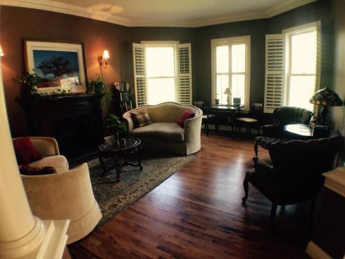 Cozy living room with a fireplace, comfortable seating, and large windows, featuring warm tones and decorative plants.
