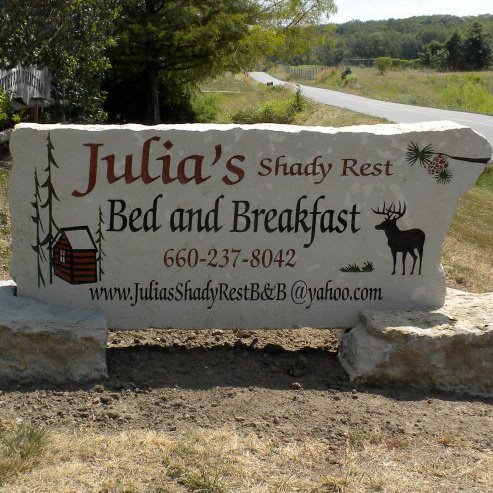 Sign for "Julia's Shady Rest Bed and Breakfast" featuring a moose and trees, with contact information.