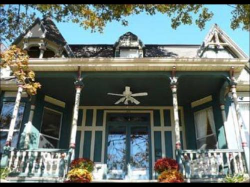Victorian-style house with a gabled roof, decorative trim, and a porch adorned with colorful flowers.
