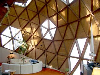 Interior of a modern room featuring a geometric wooden wall with large triangular windows and a cozy seating area.