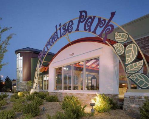 Entrance to Paradise Park, featuring a colorful arch and landscaped surroundings, illuminated at dusk.