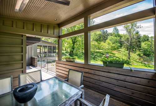 A cozy outdoor dining area with a table and chairs, overlooking a lush green landscape and trees.