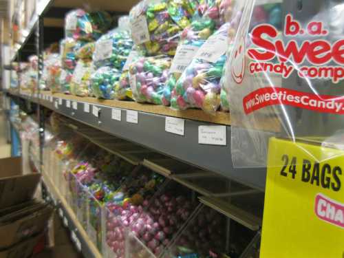 A colorful display of candy bags on shelves, with clear containers filled with assorted candies in a storage area.