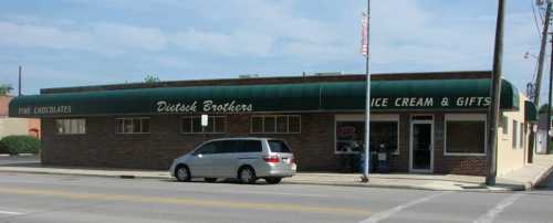 A brick building with a green awning reading "Dietsch Brothers Ice Cream & Gifts" and a minivan parked outside.