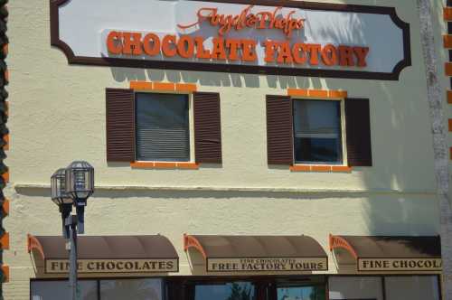 Exterior of a chocolate factory with a sign reading "Chocolate Factory" and windows above a storefront offering tours.