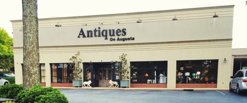 Exterior of "Antiques On Augusta" store, featuring large windows and a welcoming entrance with decorative elements.