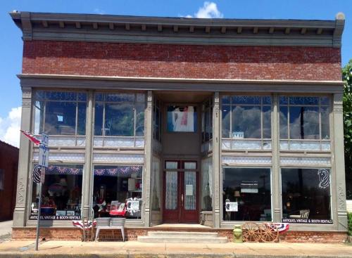 Historic brick building with large windows, featuring a boutique and decorative elements like bunting and outdoor seating.