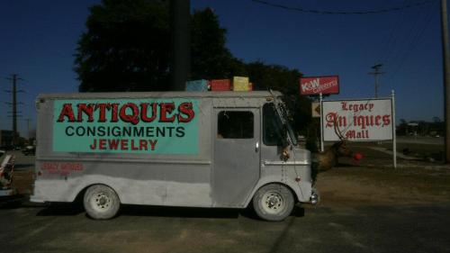 A vintage truck with "Antiques, Consignments, Jewelry" signage parked near an antiques mall sign.