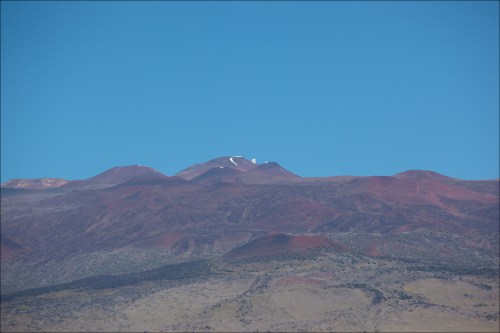 A panoramic view of rugged mountains under a clear blue sky, with some snow visible on the peaks.