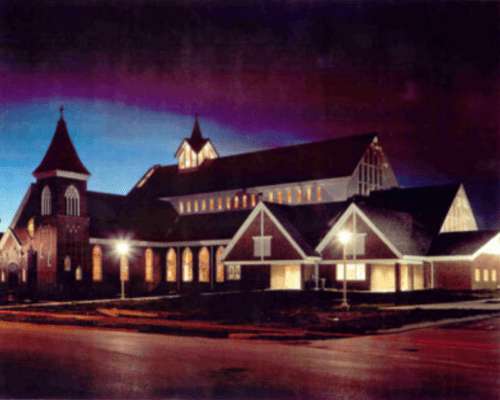A beautifully lit church at dusk, showcasing its architectural details against a darkening sky.