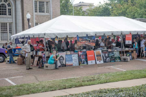 A large tent filled with people browsing books and displays at an outdoor event.