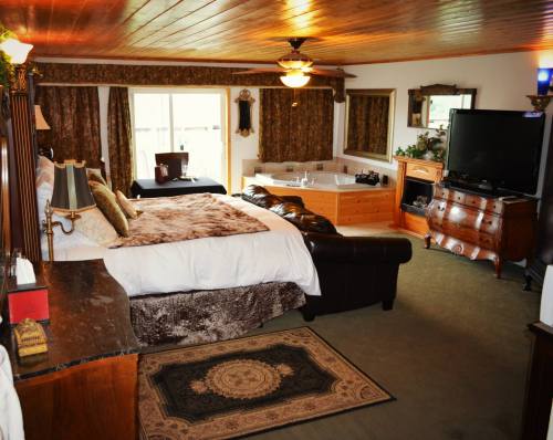 Cozy hotel room featuring a king bed, seating area, jacuzzi, and large windows with natural light.