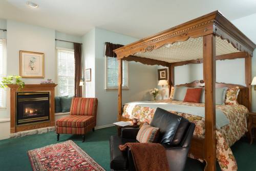 Cozy bedroom featuring a four-poster bed, fireplace, and comfortable seating with floral decor and soft lighting.