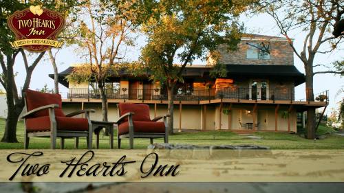 A cozy inn with a spacious porch, surrounded by trees and outdoor seating, featuring a sign that reads "Two Hearts Inn."