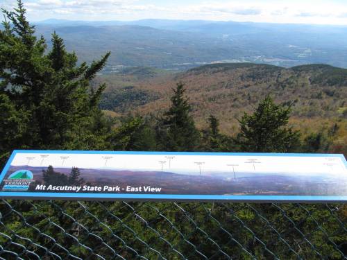 View from Mt. Ascutney State Park showcasing a panoramic landscape with a sign indicating various landmarks.