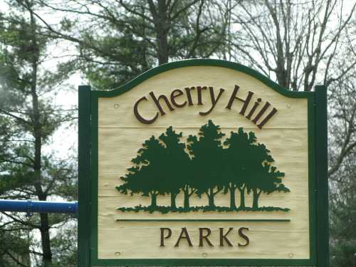 Sign for Cherry Hill Parks featuring trees and a green and yellow color scheme.