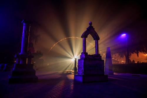 Mysterious scene with illuminated pillars and beams of light cutting through fog at night.