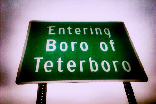 Green road sign that reads "Entering Boro of Teterboro" against a cloudy sky.
