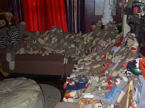 A couch covered with numerous sock monkeys, creating a whimsical and cluttered scene in a cozy room.