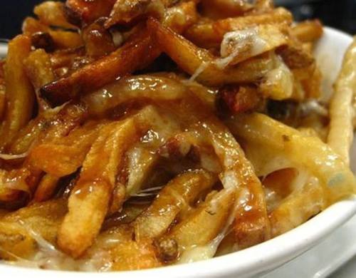A close-up of a bowl of cheesy fries topped with a rich, savory sauce.
