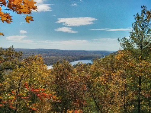 A scenic view of a river winding through colorful autumn trees under a clear blue sky.