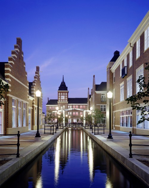 A serene canal lined with brick buildings and lampposts, reflecting a twilight sky.