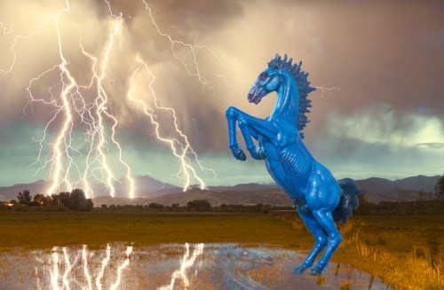 A blue toy horse rears up in a stormy landscape with lightning striking in the background and a reflective puddle in the foreground.