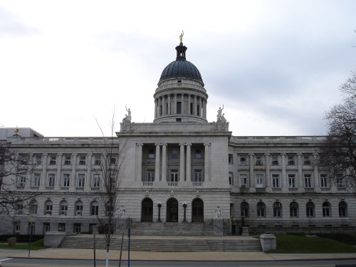 A grand government building with a dome and statues, featuring large columns and a staircase in front.