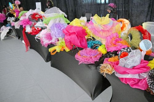 A display of colorful hats and accessories on tables, featuring vibrant fabrics and decorations in various styles.